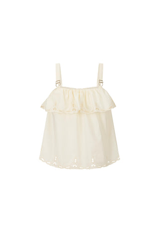 A woman modeling a cream eyelet ruffle camisole top paired with a pink floral skirt