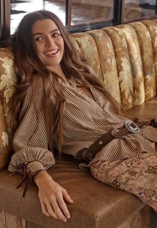  accessorized with a wide brown belt featuring silver conchos
