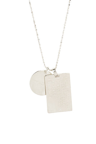 Close up back view of Spell’s Capricorn Stargazer Zodiac Necklace charms. One charm is of a rectangular shape and an inspirational quote while the other charm is circular the brand name.